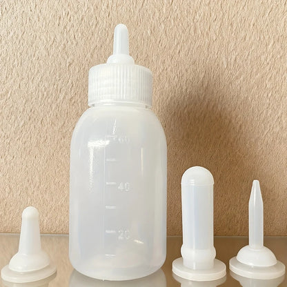 Biberon pour chaton 60 ml translucide, tétine montée, et ses trois tétines de rechange blanches de formes différentes