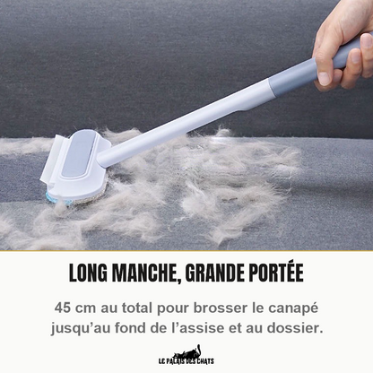 Brosse anti-poils à long manche passée sur un canapé gris couvert de poils