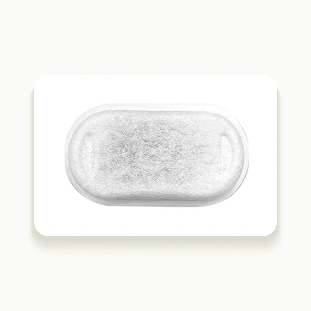 Filtre ovale en charbon actif vu de dessus, posé sur fond crème