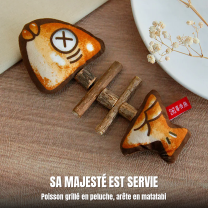 Le Festin du Roi, jouet pour chat en peluche façon poisson grillé posé sur une table près d’une assiette : Sa Majesté est servie