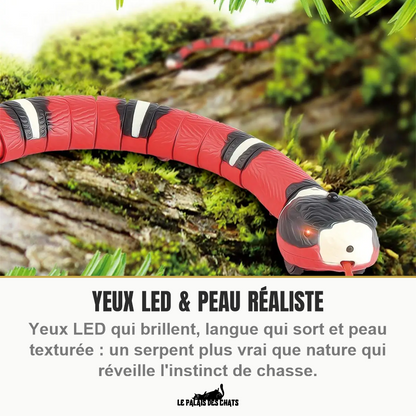 Serpent électronique pour chat sur une souche moussue, yeux LED allumés, peau texturée et langue sortie