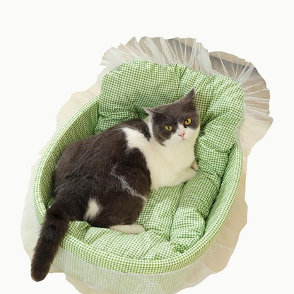 Panier pour chat ovale en vichy Le Boudoir Royal, vert pistache, avec un chat gris et blanc couché dedans