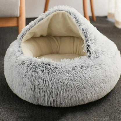 Panier rond douillet gris pour chat, capuche en fourrure longue, posé au sol du salon