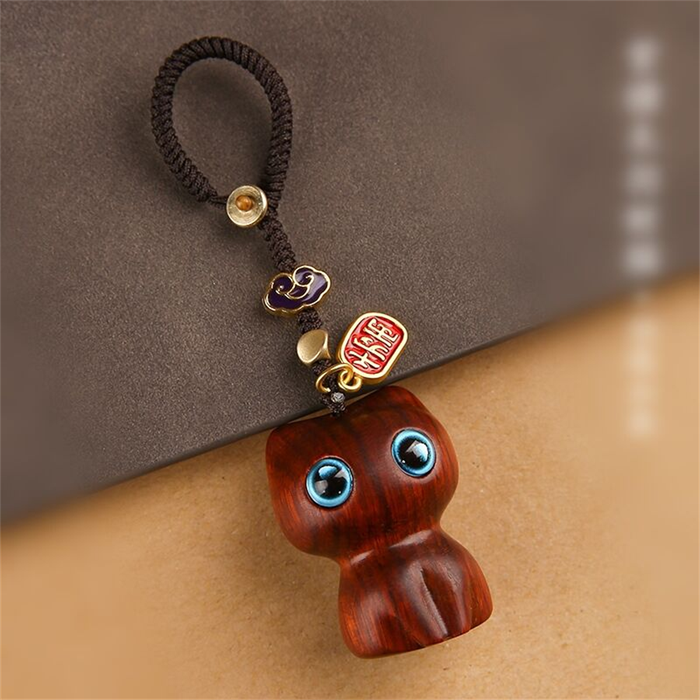 Porte-clés chat Mon Petit Grigri en finition santal rouge photographié de près : veinage du bois, perles de laiton et cordon tressé