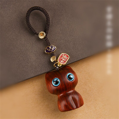 Porte-clés chat Mon Petit Grigri en finition santal rouge photographié de près : veinage du bois, perles de laiton et cordon tressé