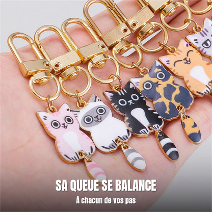 Six porte-clés chat tenus dans une main, queue articulée pendante