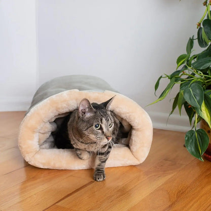 Chat tigré sortant du sac de couchage pour chat La Cachette Royale coloris Gris, sur un parquet près d'une plante
