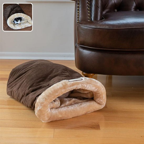 Sac de couchage pour chat La Cachette Royale coloris Marron posé sur le parquet d'un salon, près d'un fauteuil en cuir