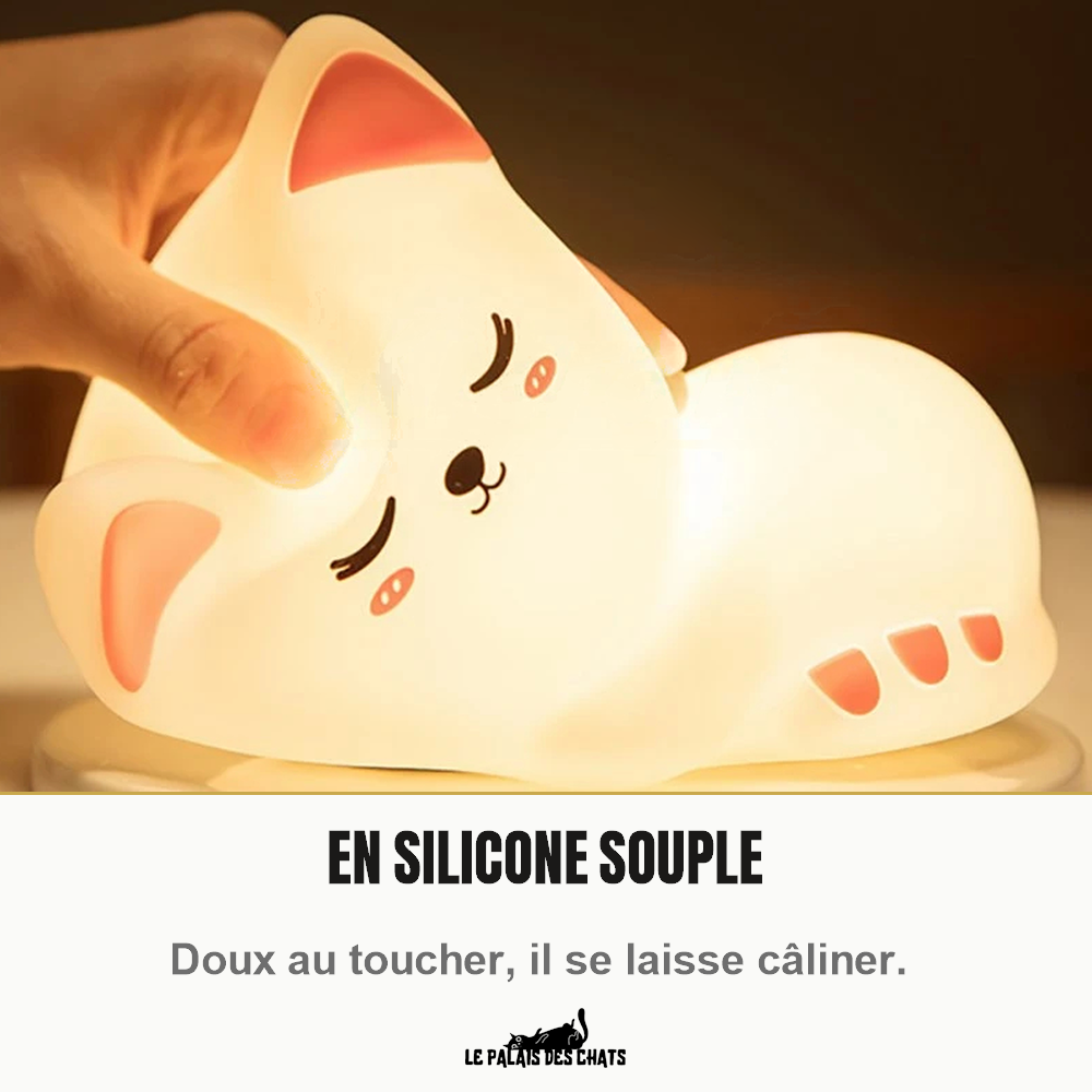 Main qui presse la veilleuse chat en silicone souple Le Veilleur Endormi, allumée en blanc chaud